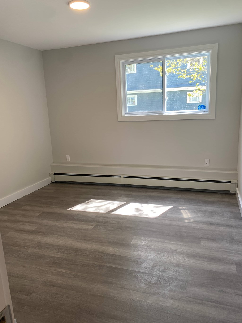 A room with a window and a floor heater.