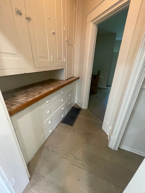 A kitchen with white cabinets and a wooden countertop.
