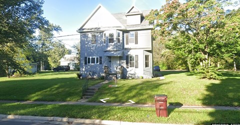 A house with a red mailbox on the lawn.