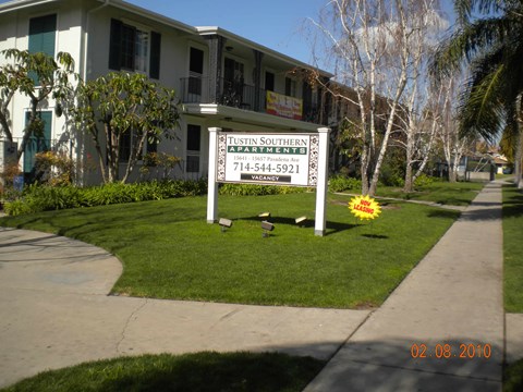 A sign for Tustin Southern Apartments stands in front of a building.