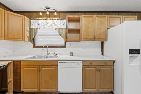 A kitchen with wooden cabinets and a white dishwasher.