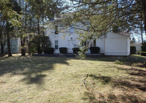 A white house with a tree in front.