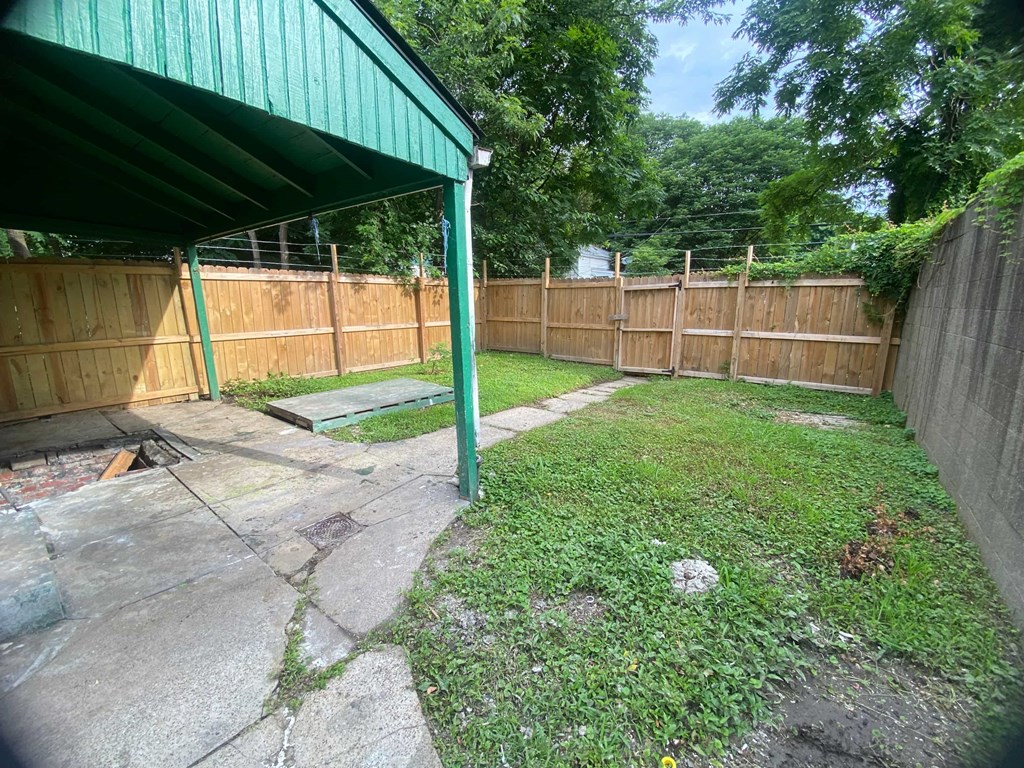 A backyard with a green metal roof and a wooden fence.