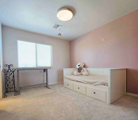 A child's bedroom with a white bed and a window with blinds.