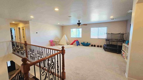 A spacious room with a ceiling fan and a play area with toys.