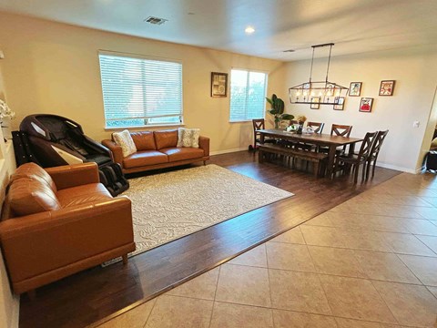 A living room with a brown leather couch and a piano.