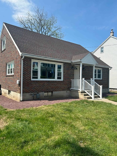 A small house with a red brick exterior and a white porch.