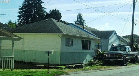 A residential street with a house and a truck parked in front.