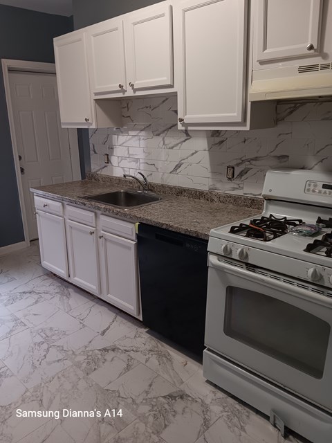A kitchen with a white stove and cabinets.
