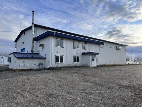 A large white building with a blue roof and a chimney.