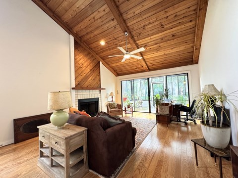 A living room with a brown couch and a wooden ceiling.