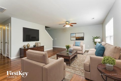 A living room with a brown sofa and a TV on the wall.