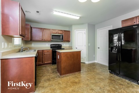 A kitchen with brown cabinets and a black refrigerator.
