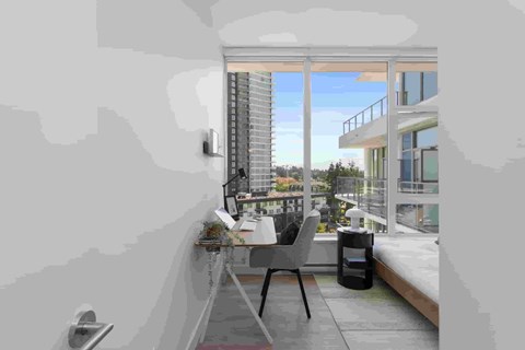 A modern balcony with a table and chairs overlooking a cityscape.