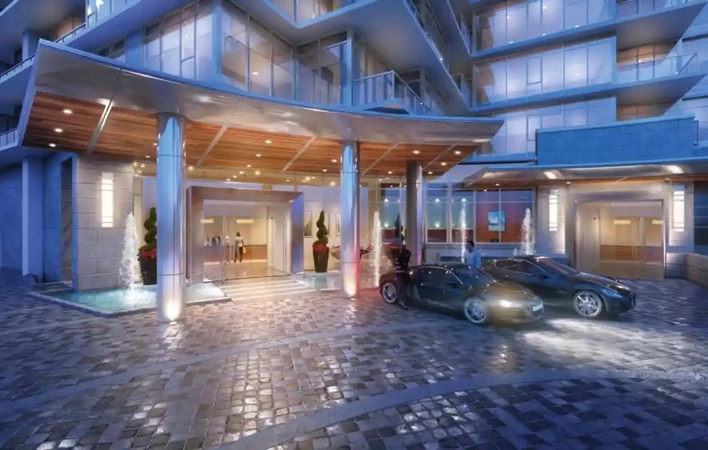 A car is parked in front of a building with a pool.