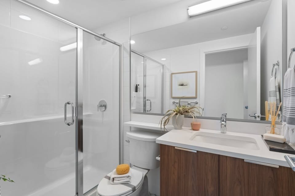 A modern bathroom with a white sink and a glass shower stall.