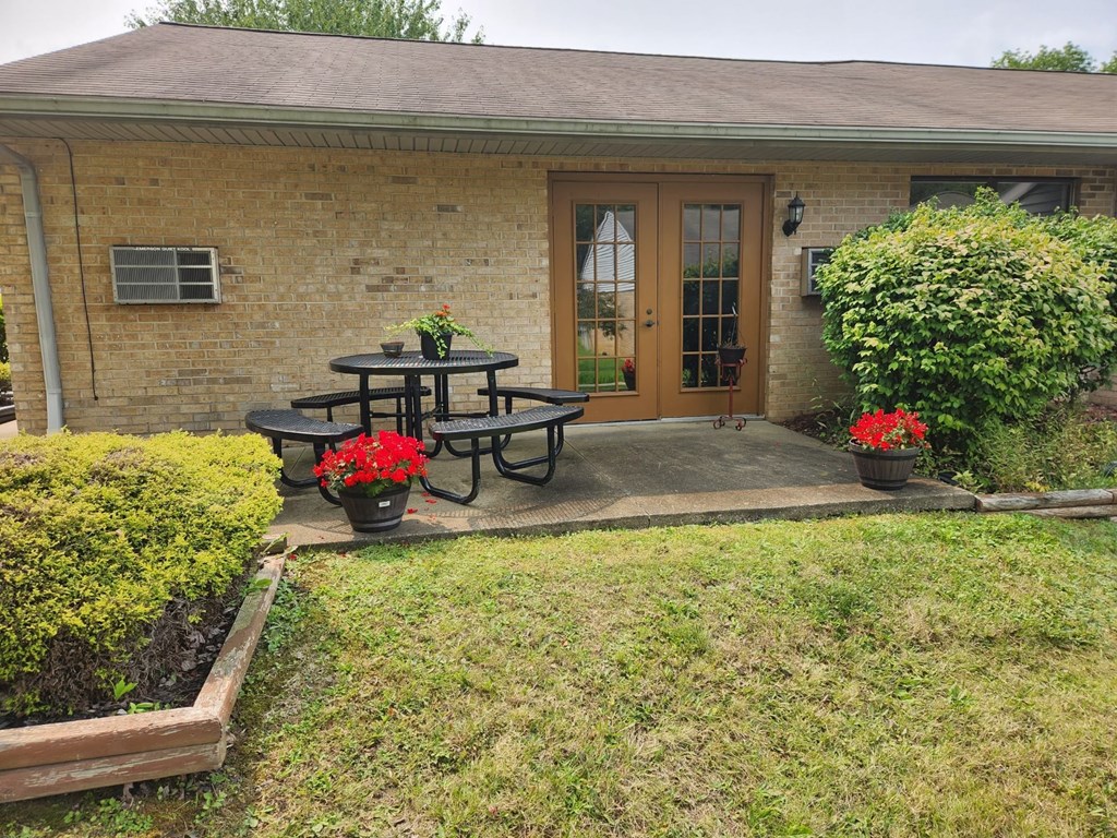 A patio with a table and chairs is in front of a house.