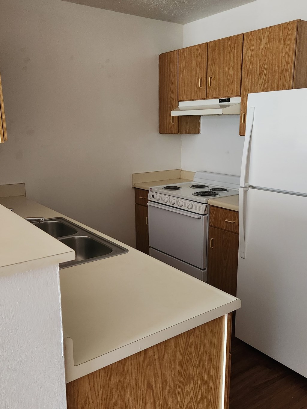 A kitchen with a white fridge, stove and oven.