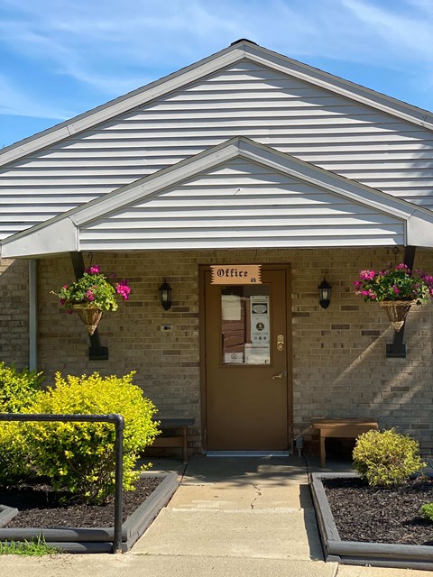 The front of a building with a brown door and a sign that says Office.