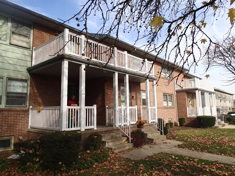 A person is standing on the porch of a brick house.