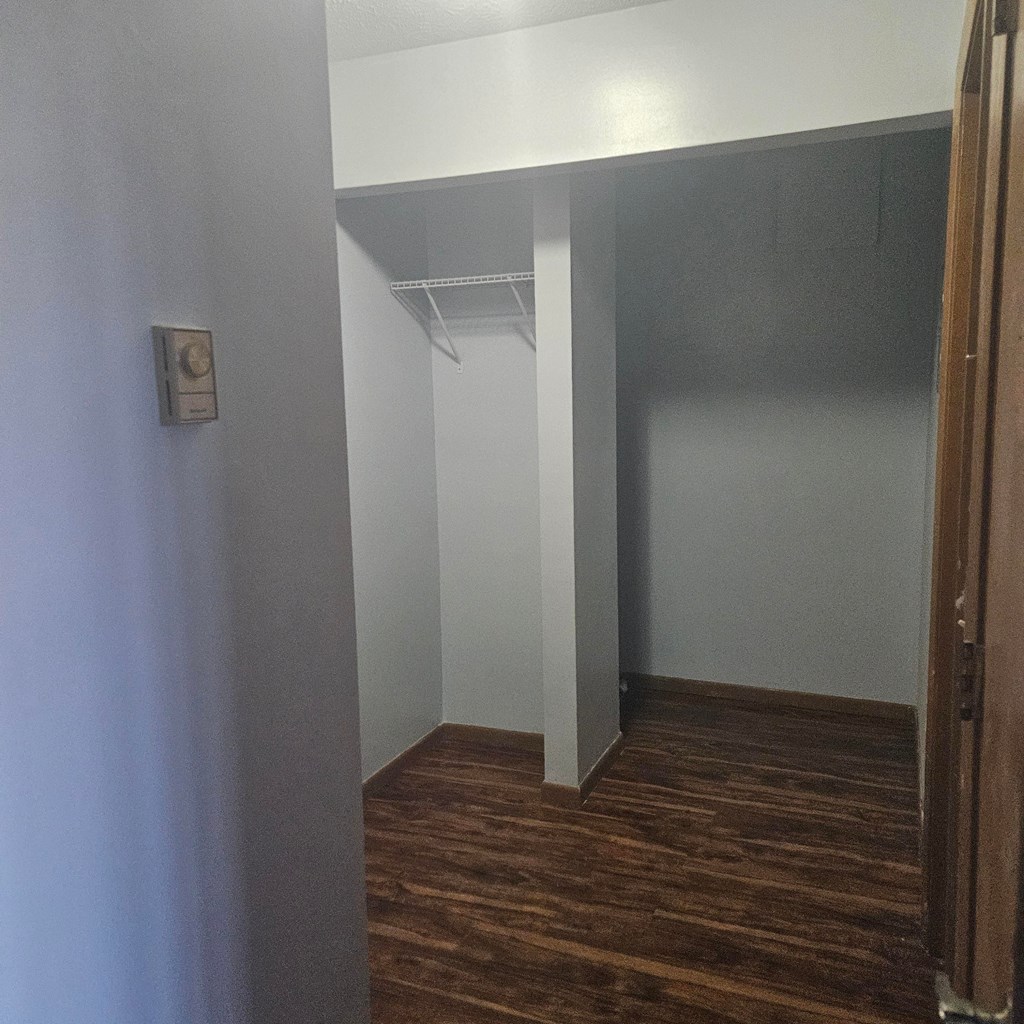 A room with a white wall and a brown floor.