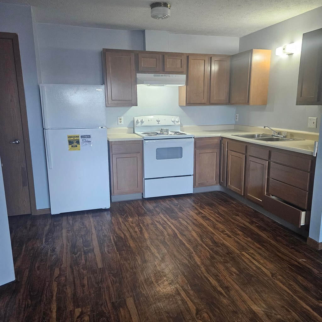 A kitchen with wooden floors and white appliances.