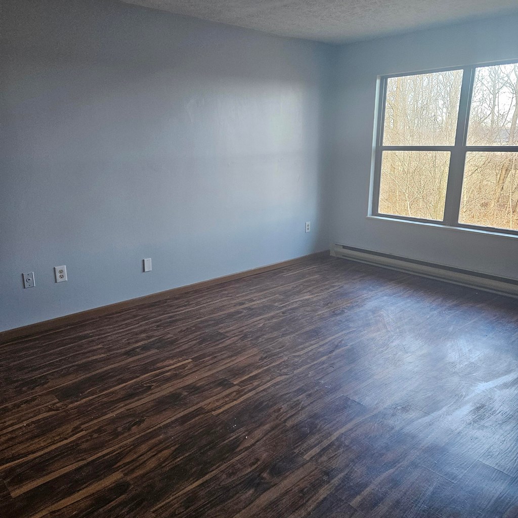 A room with a window and wooden flooring.