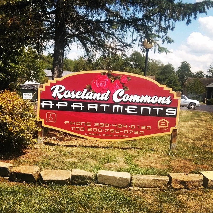 A sign for Roseland Commons Apartments with phone numbers listed.