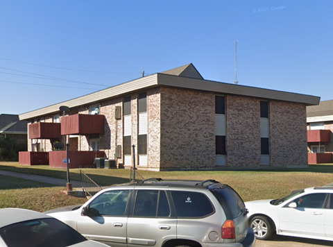 A silver car is parked in front of a building with a red and white striped wall.