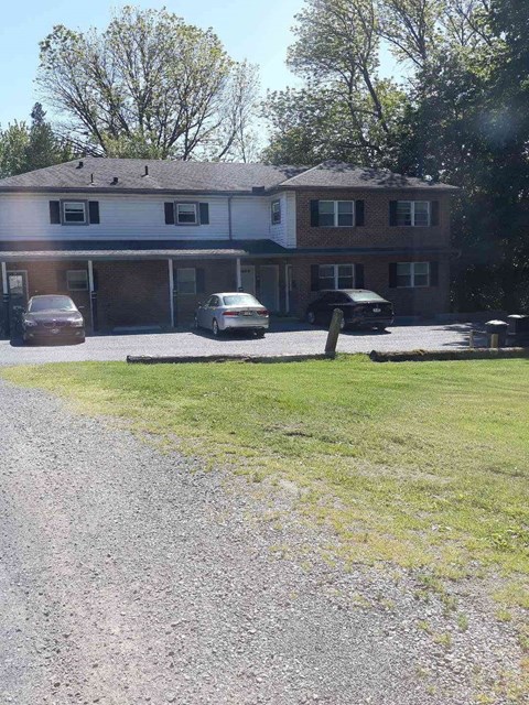 A house with a gravel driveway and a car parked in front.