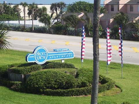 A sign for Shore View Apartments is in front of a building and palm trees.