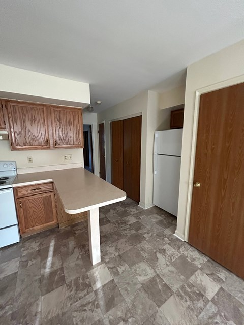 A kitchen with a white table and brown cabinets.