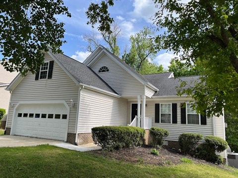 A house with a white garage door and a brick pillar.