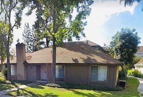 A house with a brown roof and a chimney is surrounded by trees.