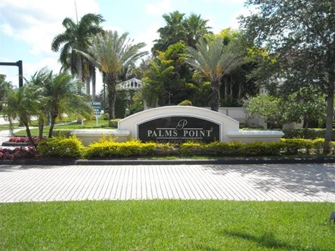 A sign that says Palms Point in front of some trees.