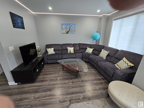 A living room with a grey couch and a wooden floor.