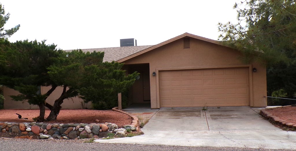 A house with a brown garage door and a tree in front.