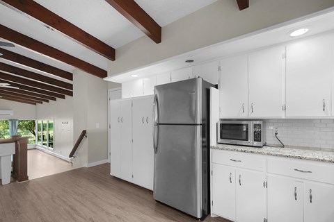A kitchen with white cabinets and a stainless steel refrigerator.
