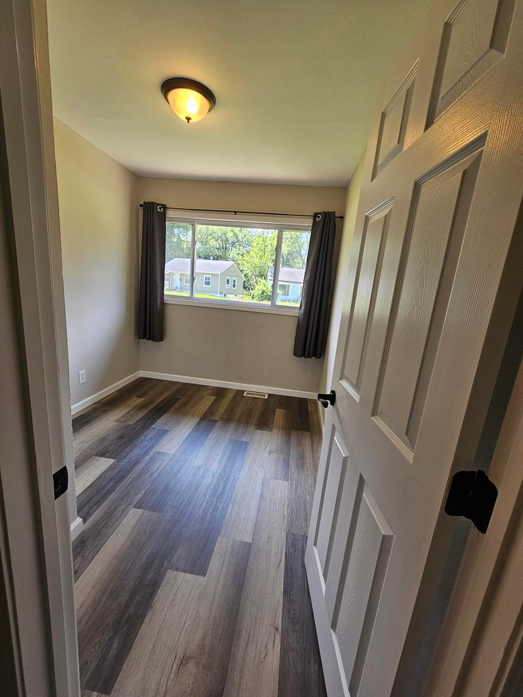A hallway with a wooden floor and white walls.
