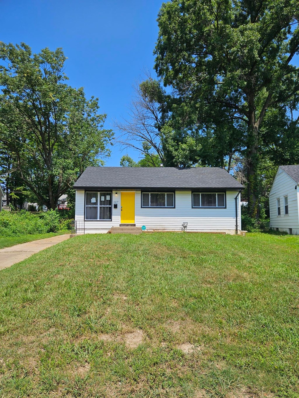 A small house with a yellow door is surrounded by greenery.