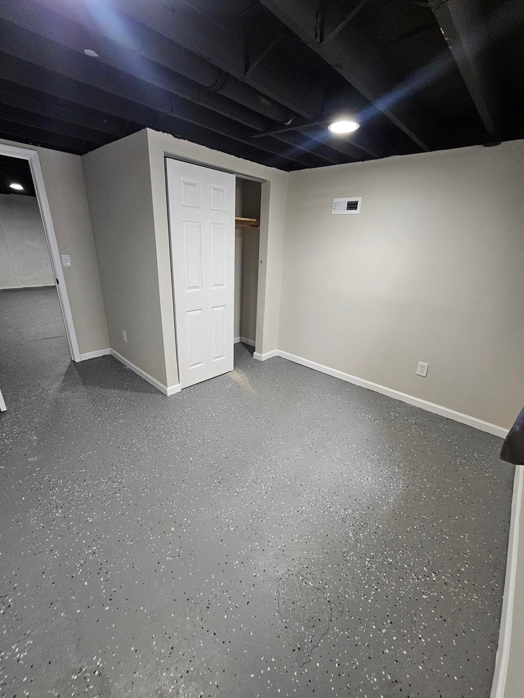 A room with a grey floor and a white door.