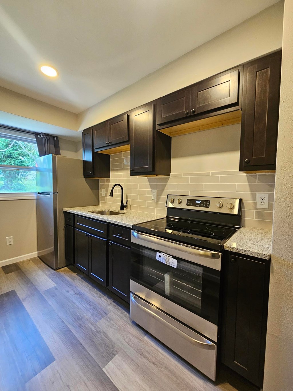 A kitchen with black cabinets and a stove top oven.