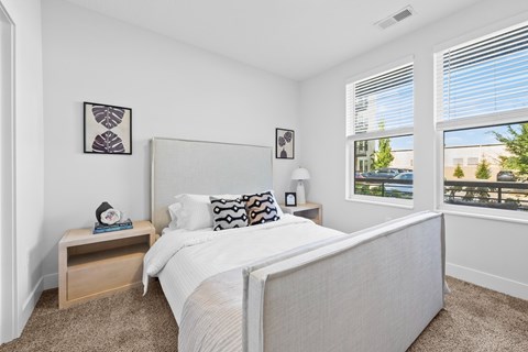 A bedroom with a large bed and a window overlooking a balcony.