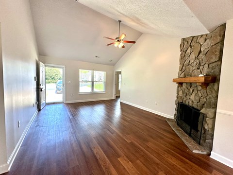 A room with a stone fireplace and wood flooring.