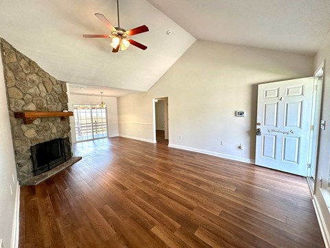 A room with a stone fireplace and wood flooring.