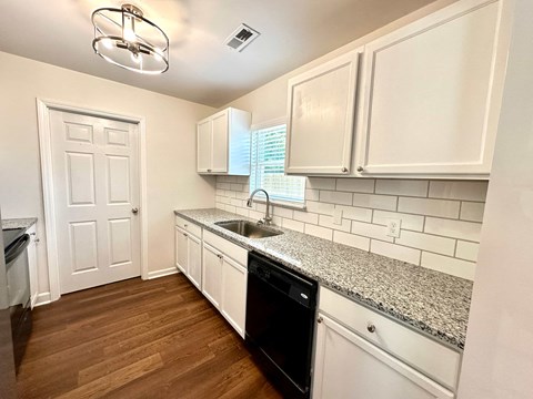 A kitchen with white cabinets and a black dishwasher.