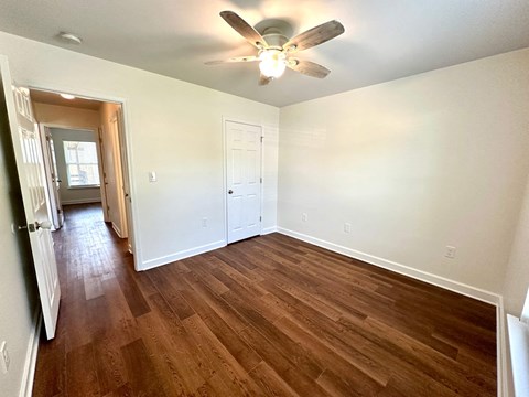 A room with a ceiling fan and wooden flooring.