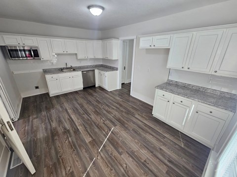 A kitchen with white cabinets and a wooden floor.