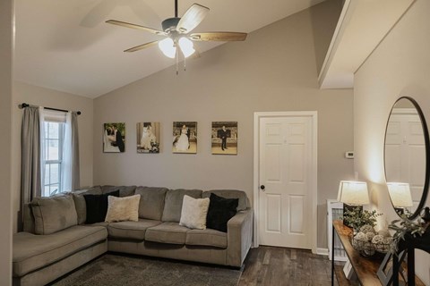 A living room with a grey couch and a ceiling fan.