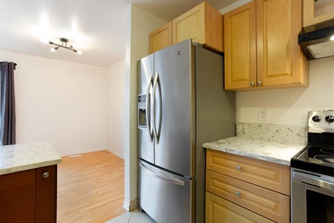 A kitchen with a stainless steel refrigerator and wooden cabinets.